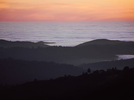 Stunning sunrise view over misty hills and ocean, capturing the tranquil beauty of nature's awakening.
