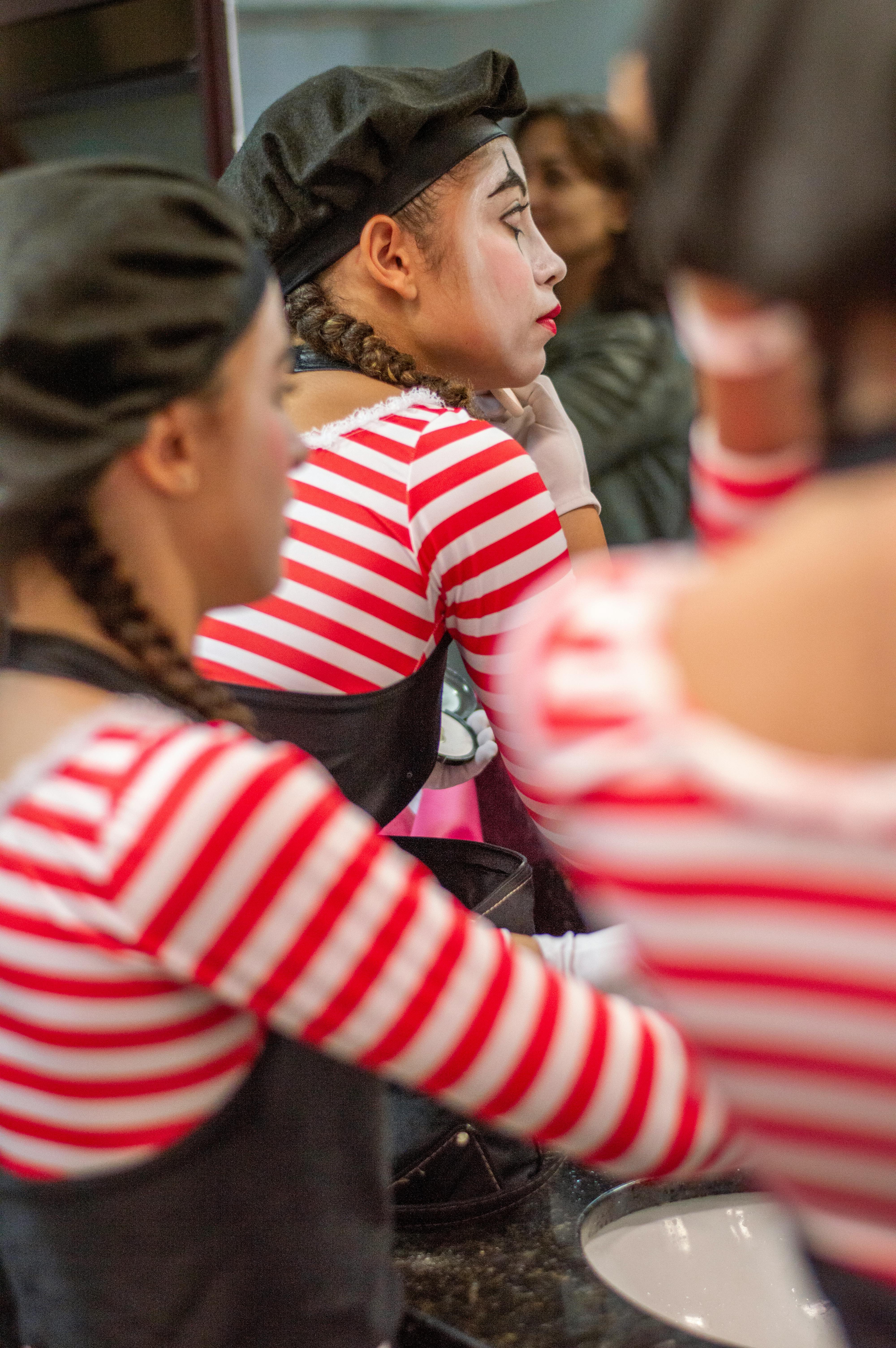Free A young woman applies stage makeup in a dressing room before performance, wearing a striped costume. Stock Photo