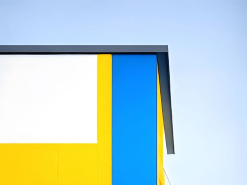 Free Contemporary building exterior with vibrant yellow and blue facade against clear sky. Stock Photo