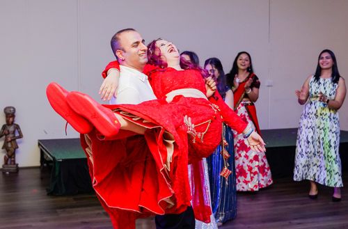 Free A man joyfully carries a woman in a vibrant dress during a fun, lively dance party. Stock Photo