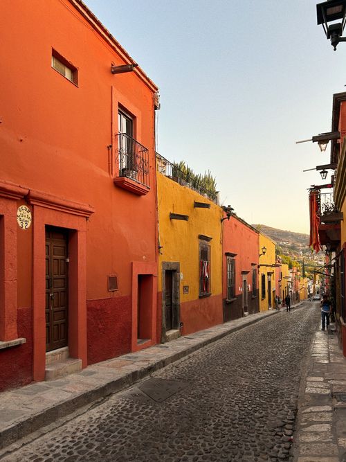 Free Colorful cobblestone street in San Miguel de Allende, showcasing vibrant traditional architecture at sunset. Stock Photo
