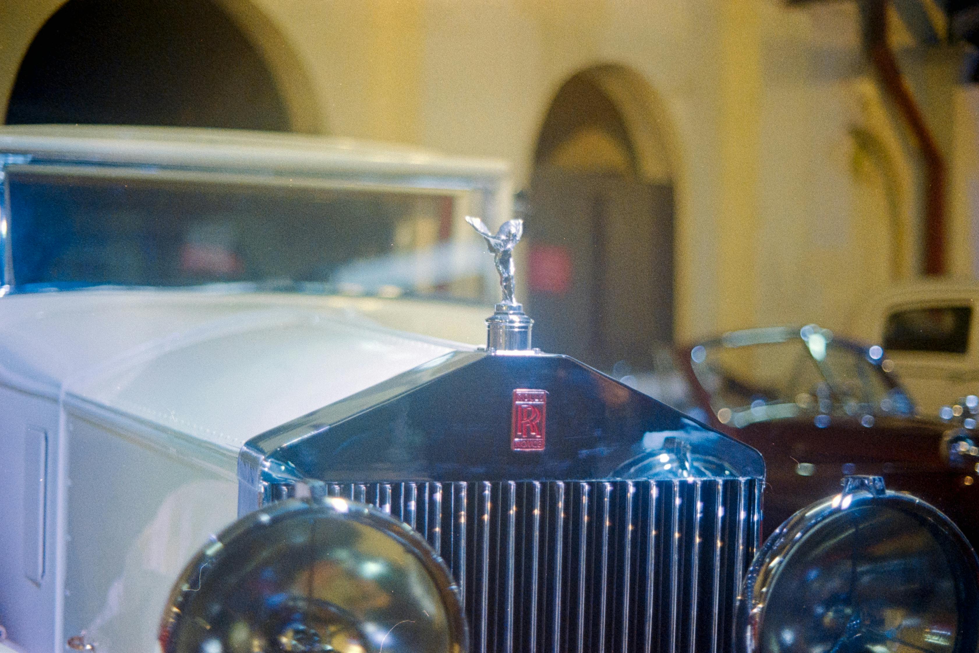 Close-up of vintage Rolls-Royce Phantom grille with iconic emblem at night.