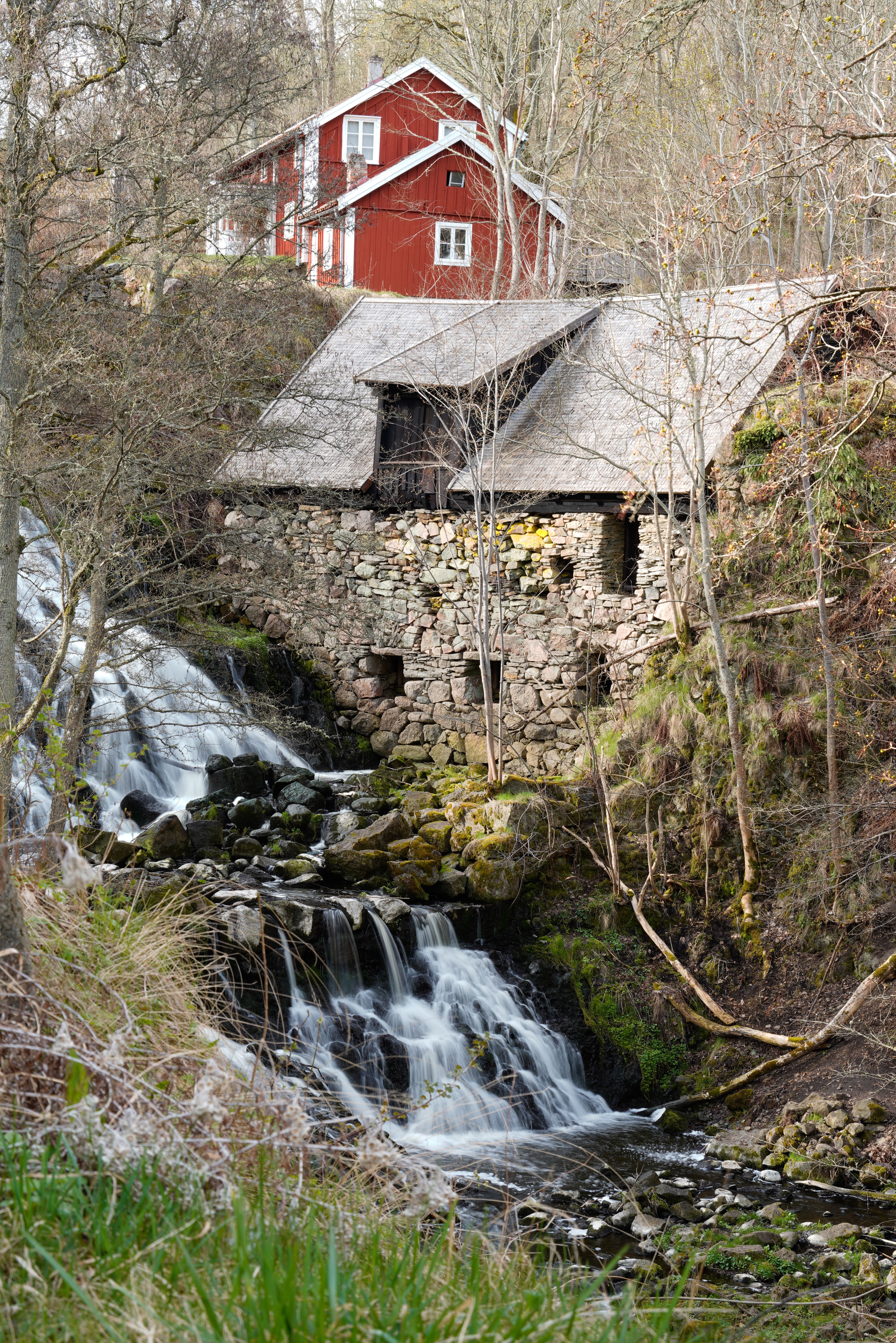 Picturesque stone cottage and waterfall in Gränna, Sweden, perfect for rural landscape photography.