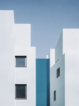 Abstract view of white and blue apartment buildings with a clear sky.