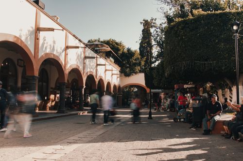 Free Vibrant urban street scene with bustling crowds and arched building facade. Stock Photo