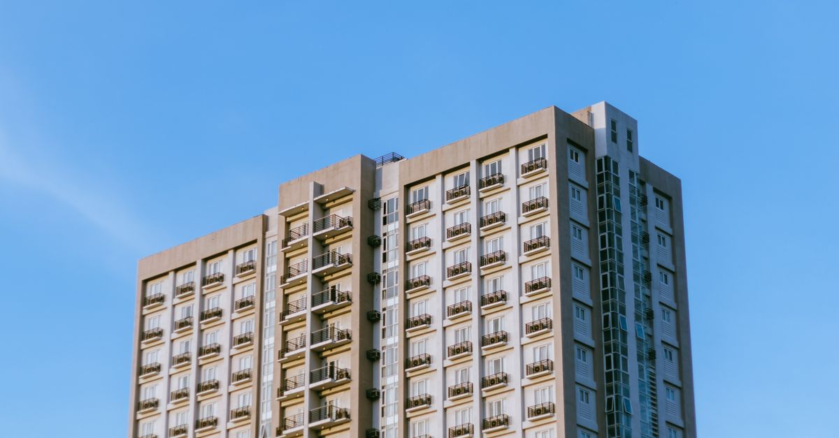 Contemporary high-rise apartment building with balconies under a clear blue sky.