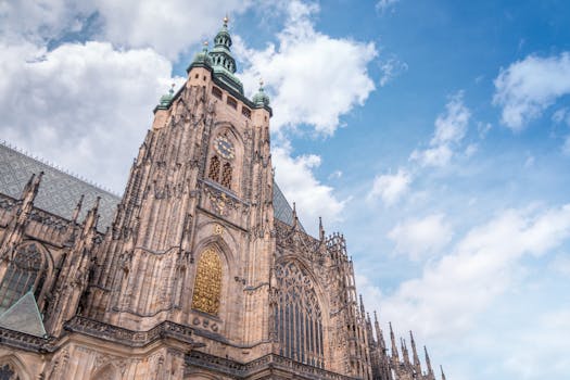 Low angle view of a Gothic cathedral tower with ornate architecture against a vibrant blue sky.
