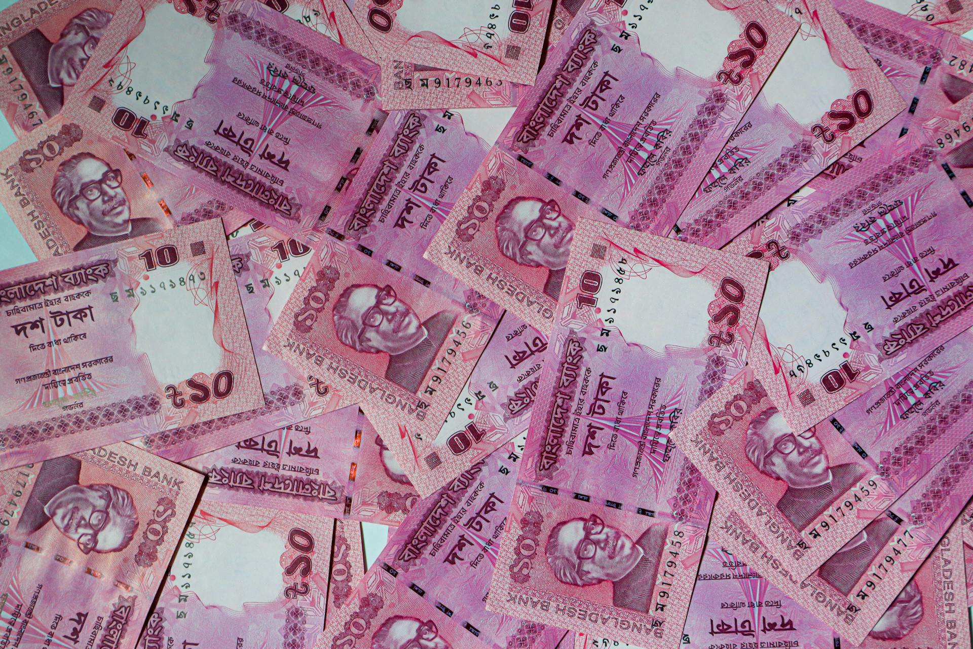 Various Bangladeshi Taka notes in a flat lay pattern, showcasing the vibrant currency.