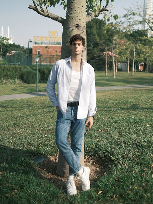 Photo of a Handsome Young Man Standing by a Tree