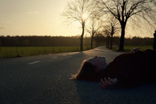 A Woman Lying on a Road in Sunlight