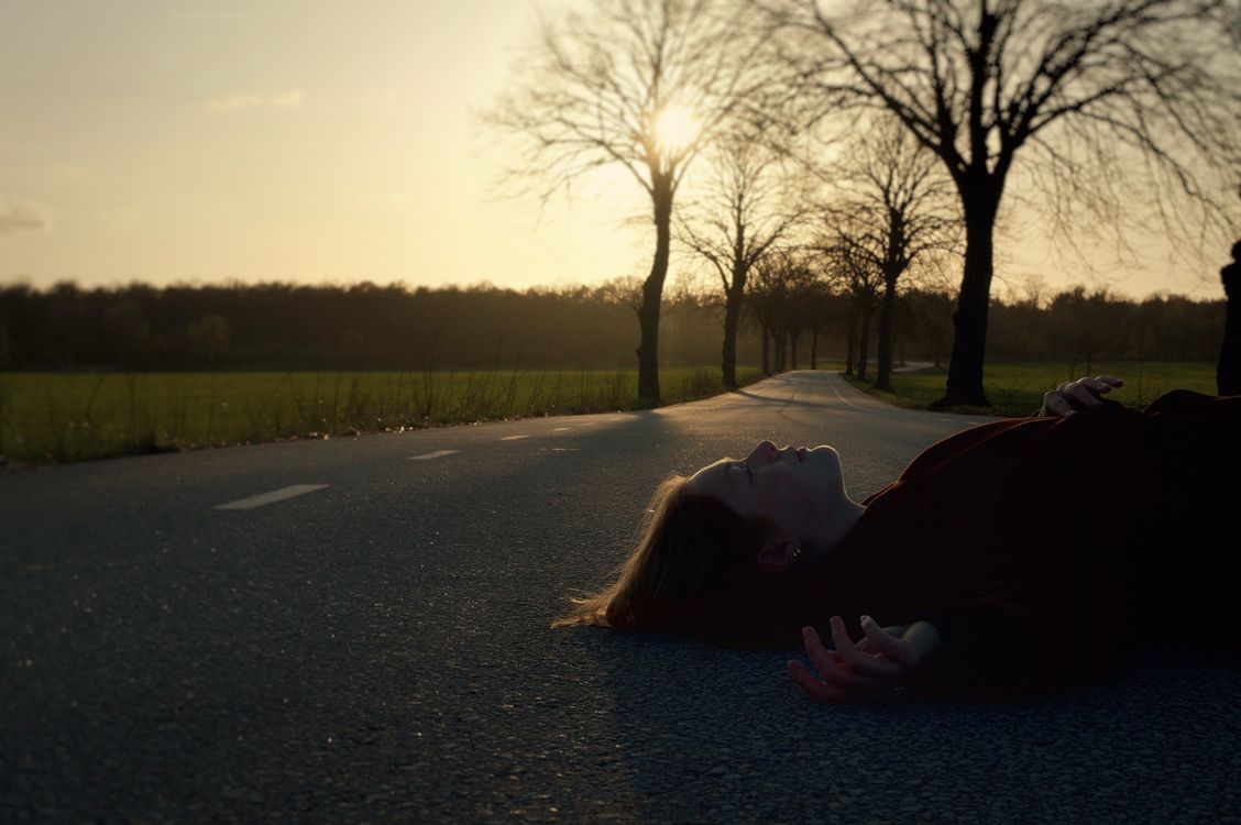 A Woman Lying on a Road in Sunlight · Free Stock Photo