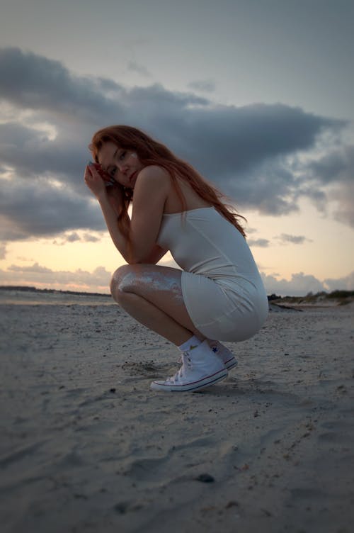 Photo of a Cute Young Woman Squatting on the Beach