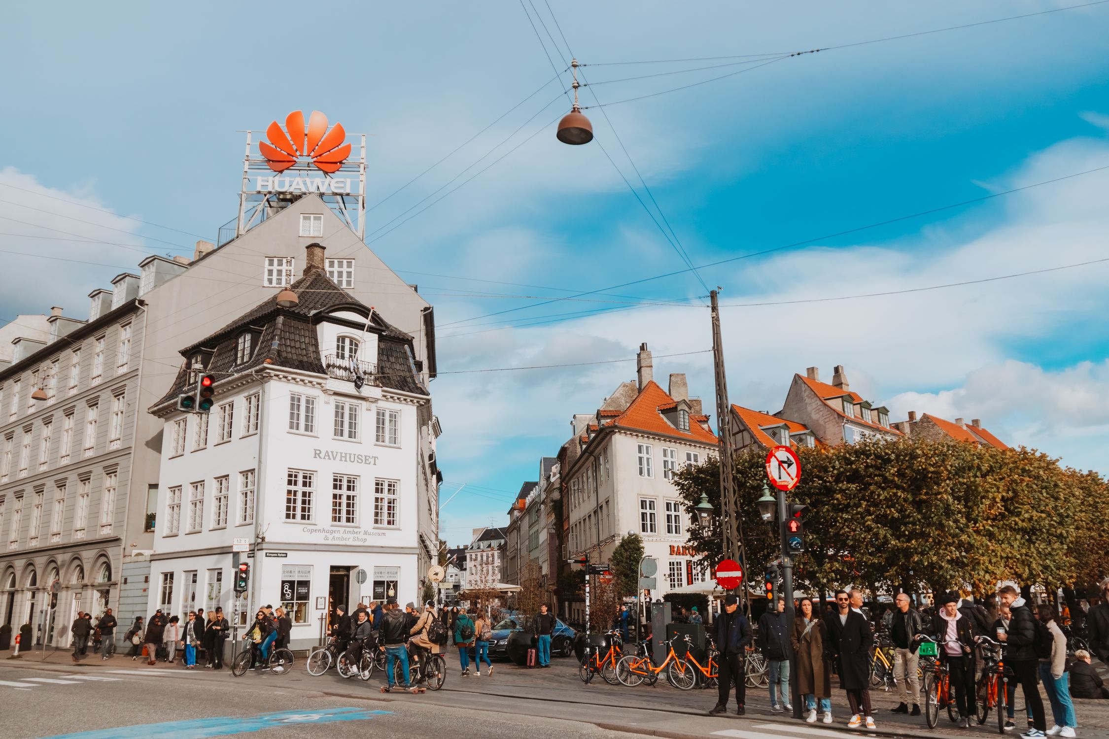 View of a busy street in Copenhagen, Denmark featuring pedestrians and historic buildings under a bright sky