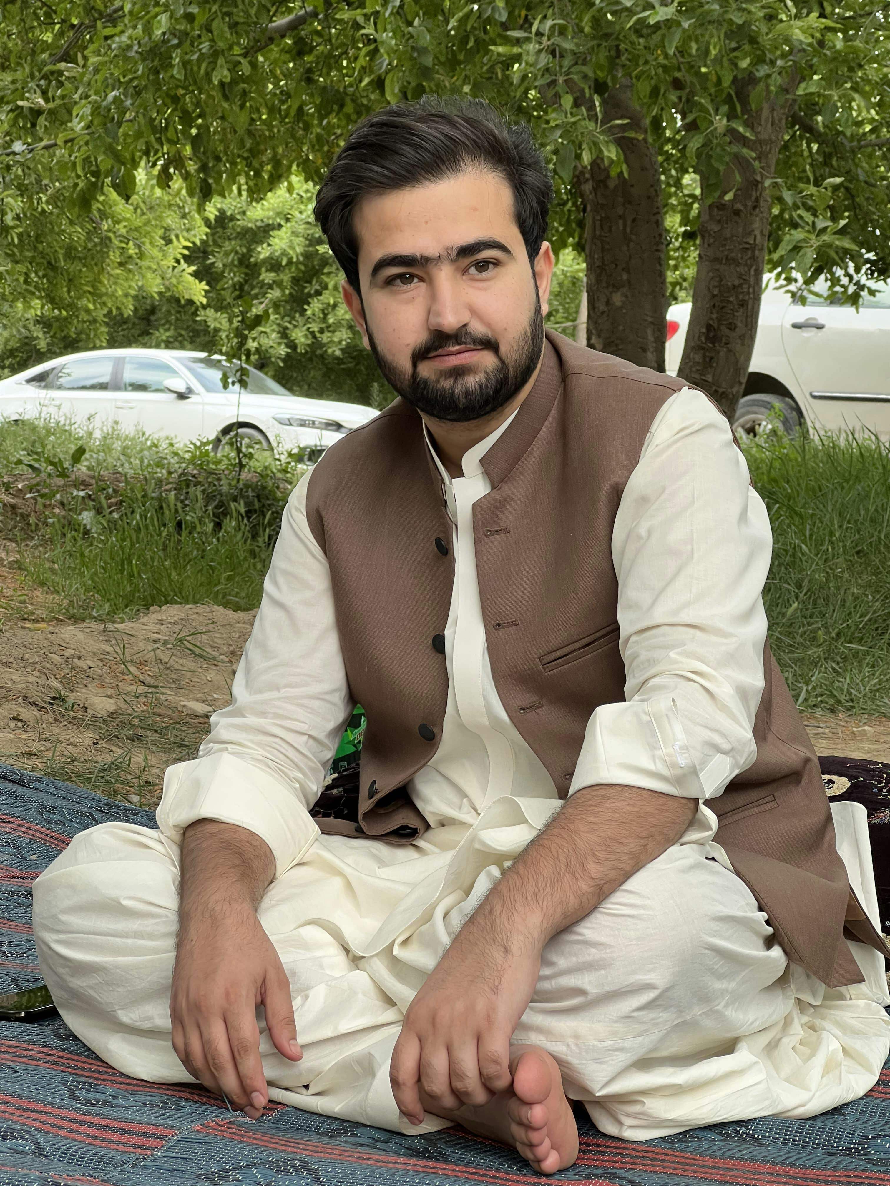 Portrait of a man in traditional clothing sitting outdoors, exuding cultural elegance.