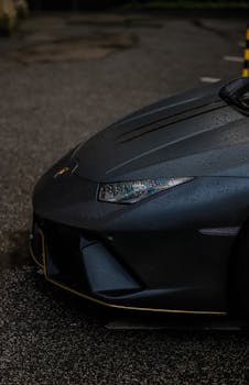 Detailed close-up of a wet luxury sports car headlight on a rainy day.