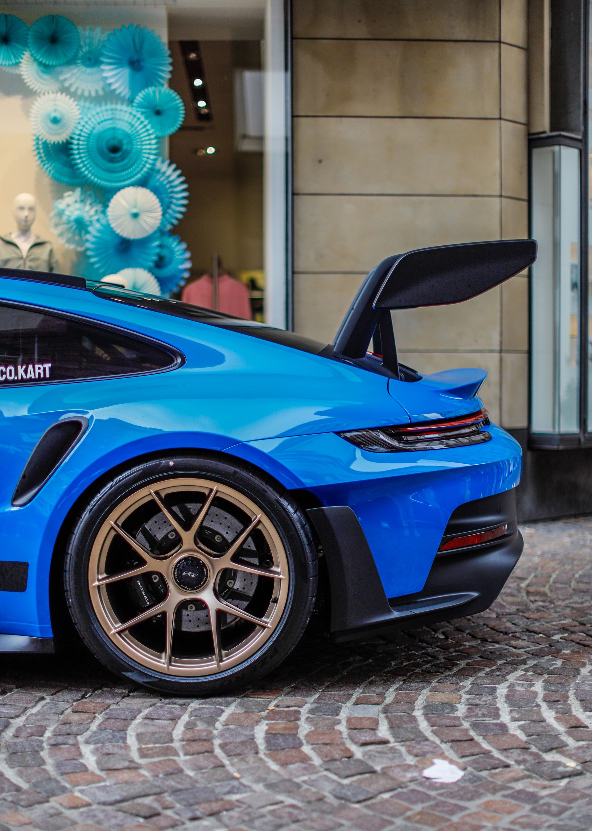 Blue sports car gleaming on cobblestones after a wash