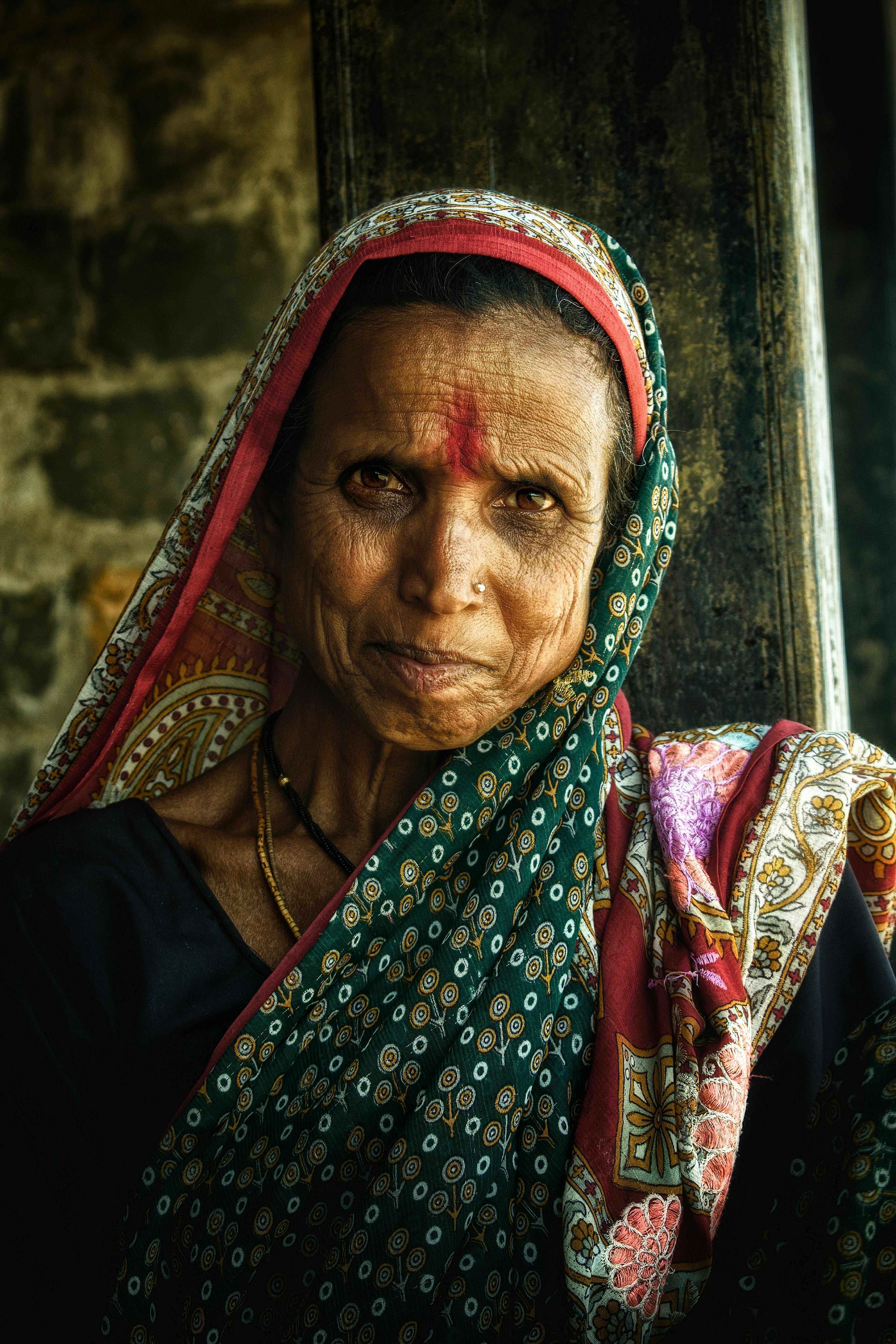 Elderly woman wearing a vibrant headscarf and traditional clothing, showing cultural richness.