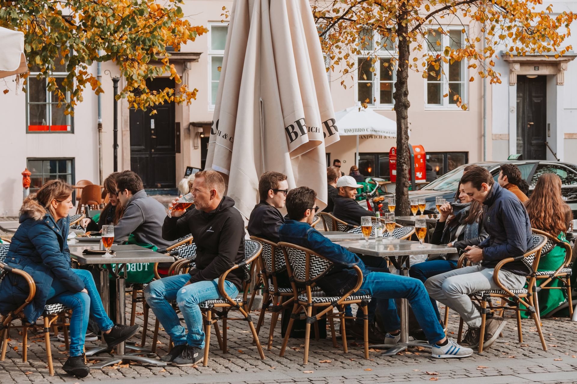 People enjoying drinks at an outdoor cafe in a vibrant urban setting.