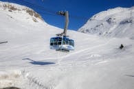 在晴朗的冬日，缆车滑过白雪覆盖的山脉