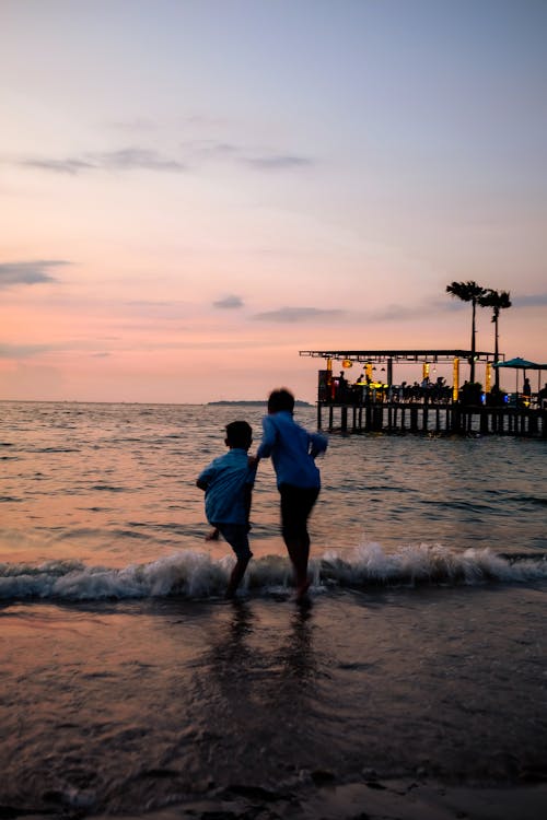 Silhouette of Kids Playing in the Sea Water at Dusk 