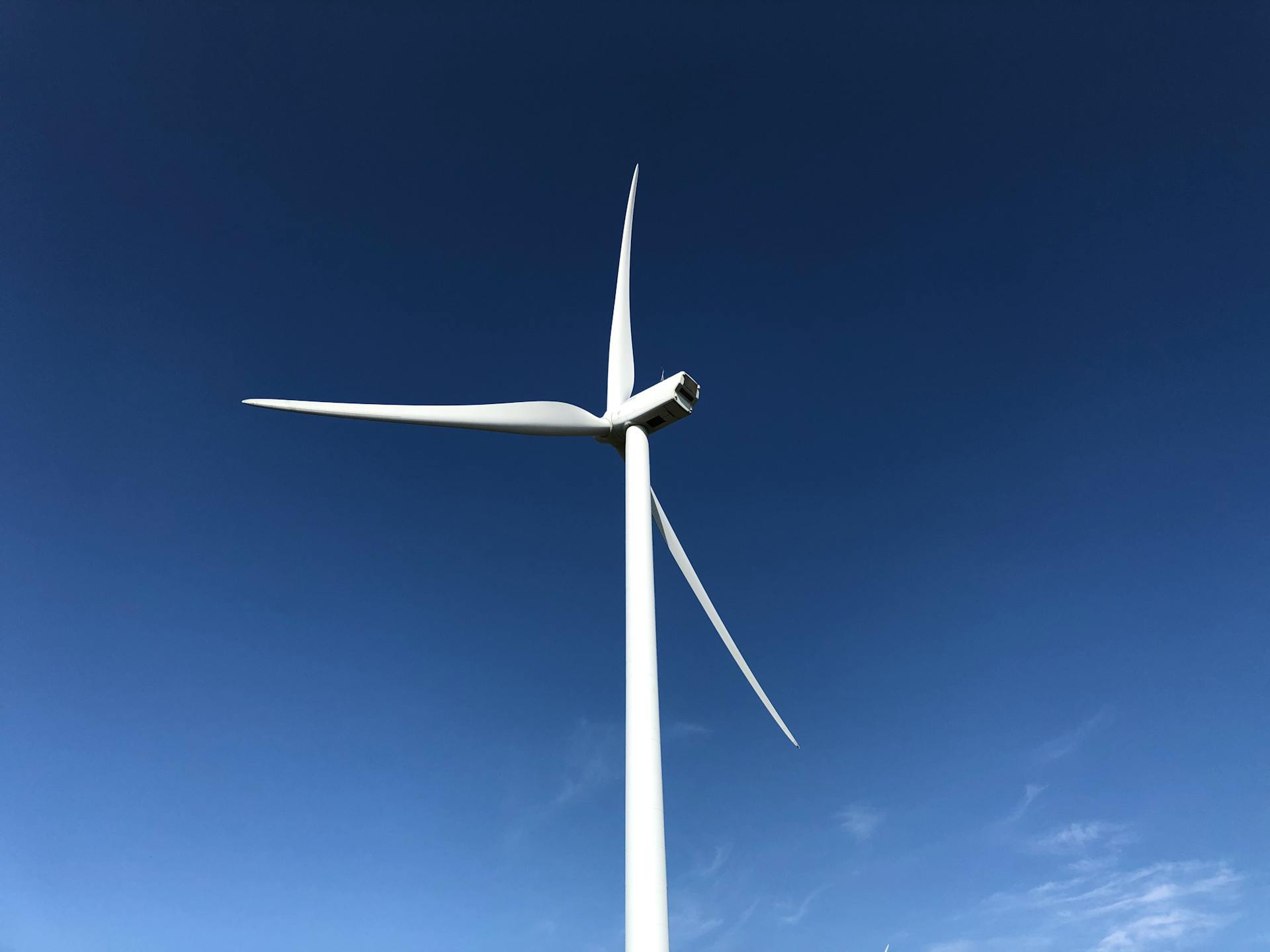 Wind turbine reaching towards a clear blue sky, representing renewable energy in Italy.