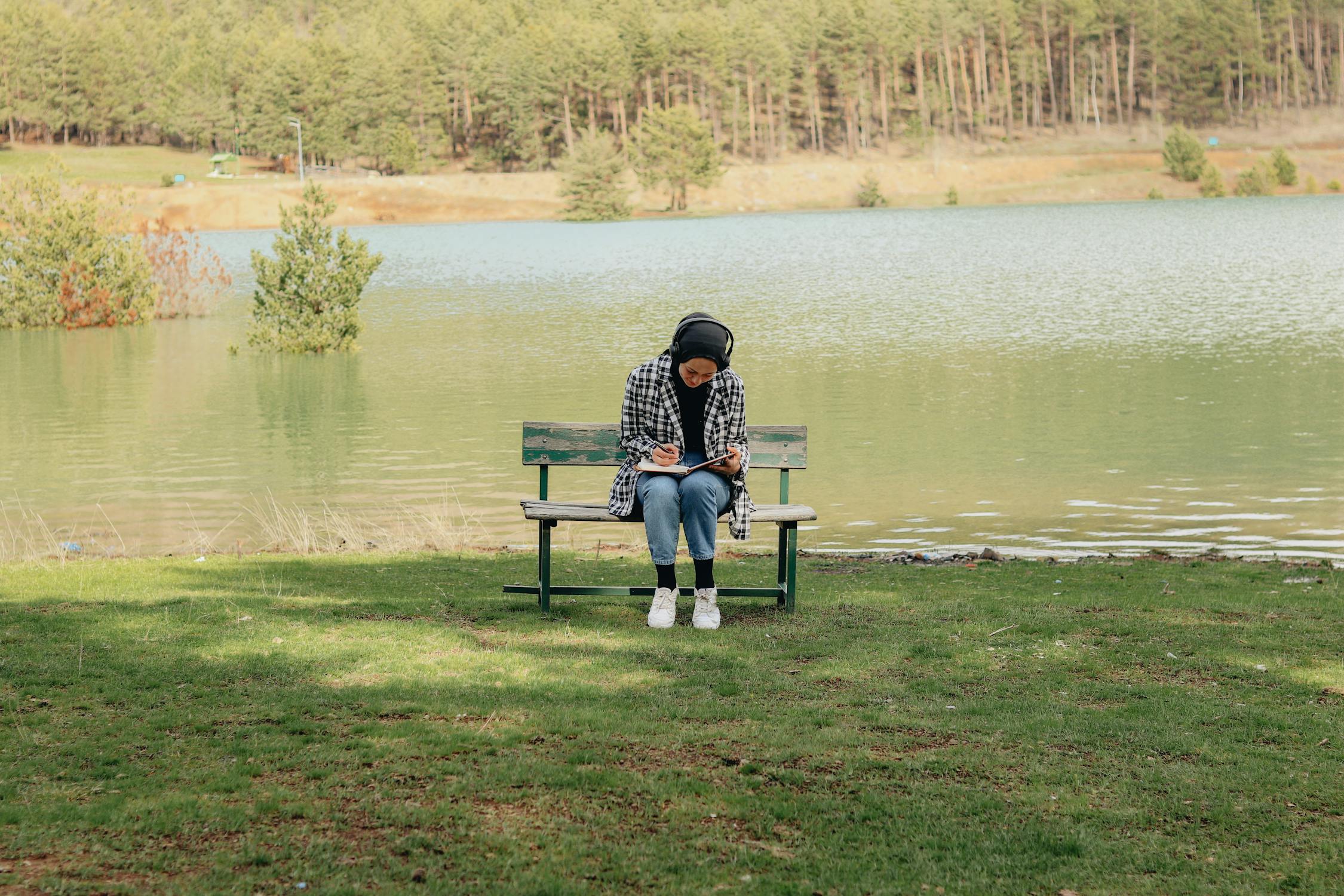 free photo of a person sitting on a bench by a lake