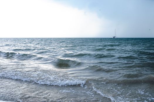 Calm waves and a distant yacht on the serene sea of Jepara, Central Java.