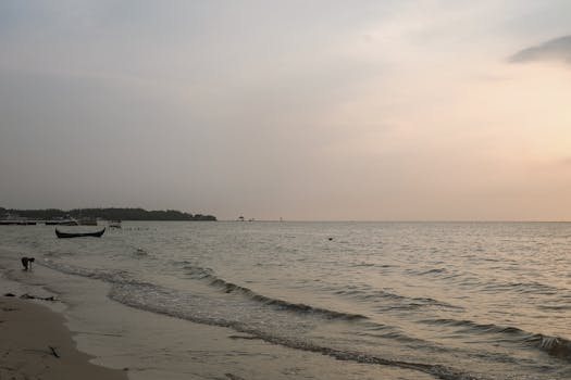 A peaceful scene at sunset on Jepara beach with gentle waves and boats.