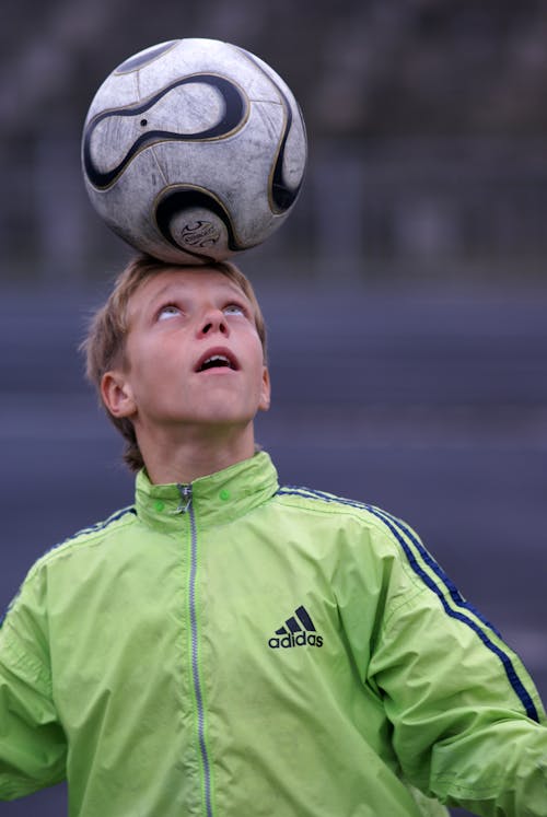 A boy balancing a soccer ball on his head