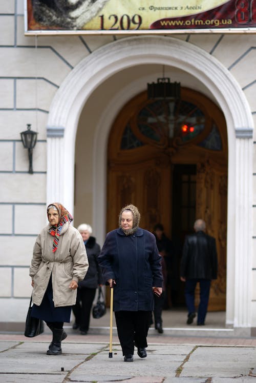 Two women walk past a building with a sign on it
