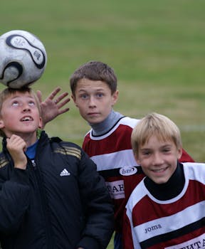 Three cheerful young boys playing soccer outdoors, capturing the joy and energy of youth sports.