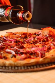 Appetizing pizza with red onion and olive oil being drizzled, perfect for food lovers.