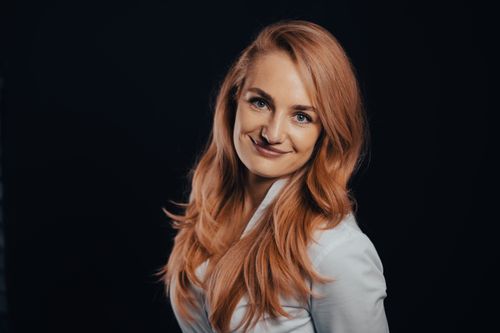 Free A confident, smiling redhead woman poses gracefully against a dark background in a studio setting. Stock Photo