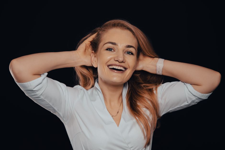 A joyful woman posing elegantly in a studio setting with a bright smile, showcasing style and confidence.