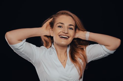 Free A joyful woman posing elegantly in a studio setting with a bright smile, showcasing style and confidence. Stock Photo
