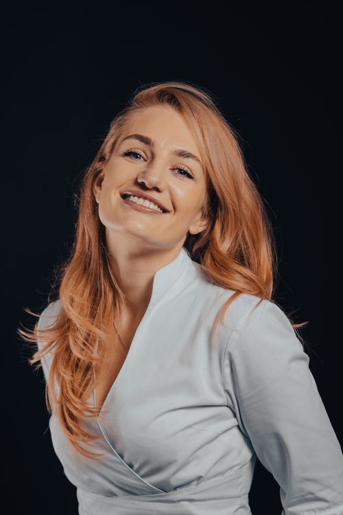 Free Portrait of a young woman with red hair smiling in a studio setting, showcasing style and elegance. Stock Photo