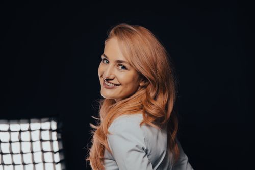 Free Smiling woman with long blonde hair posing against a dark background in a professional studio setting. Stock Photo