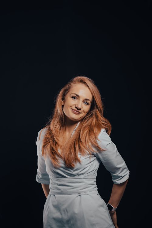 Free Portrait of a smiling woman with blonde hair against a black background, exuding confidence. Stock Photo