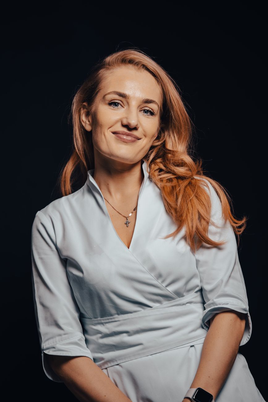 Portrait of a smiling woman in a blue dress on a black background, conveying happiness and confidence.