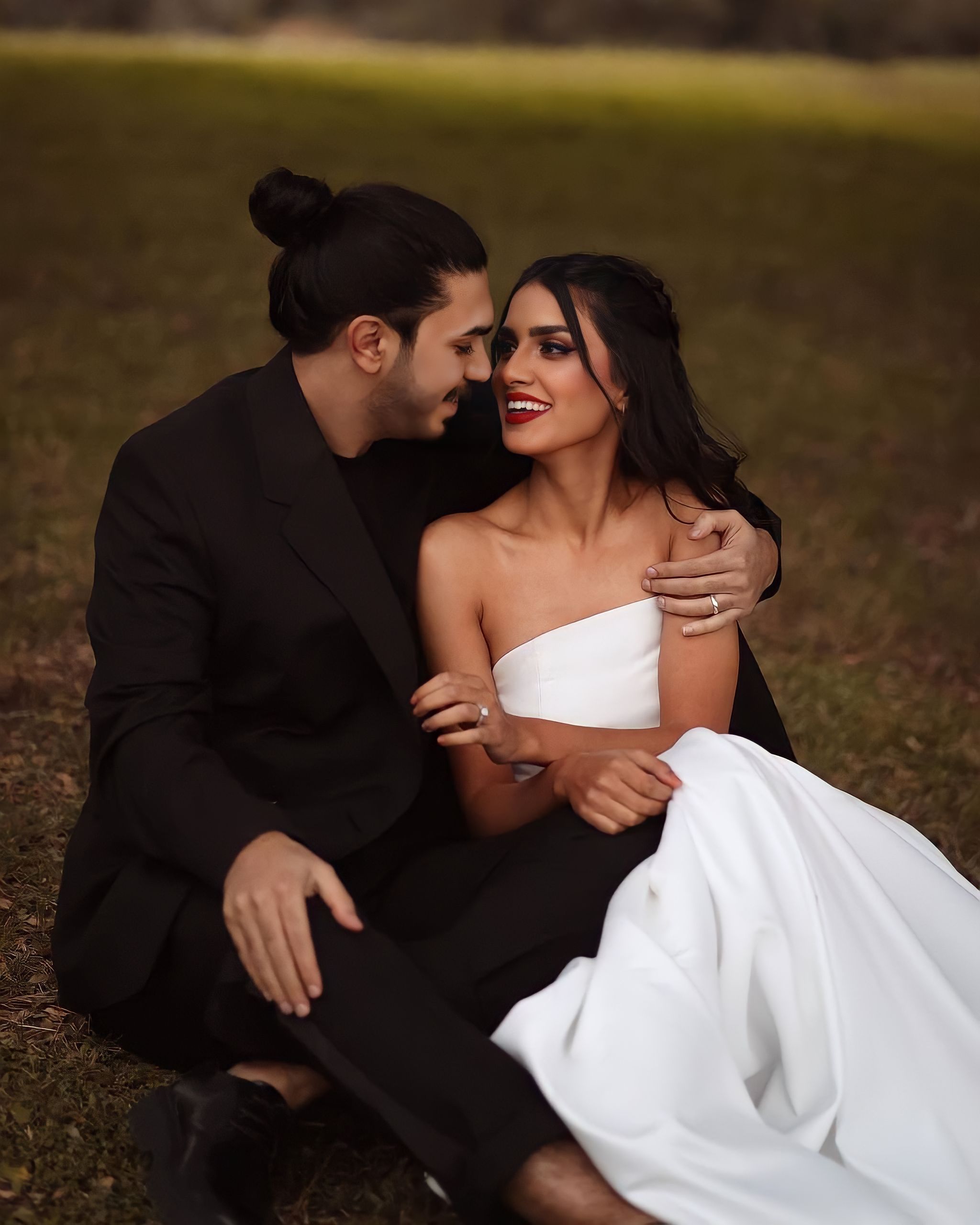 A joyful newlywed couple embraces on a grassy lawn, showcasing love and happiness.
