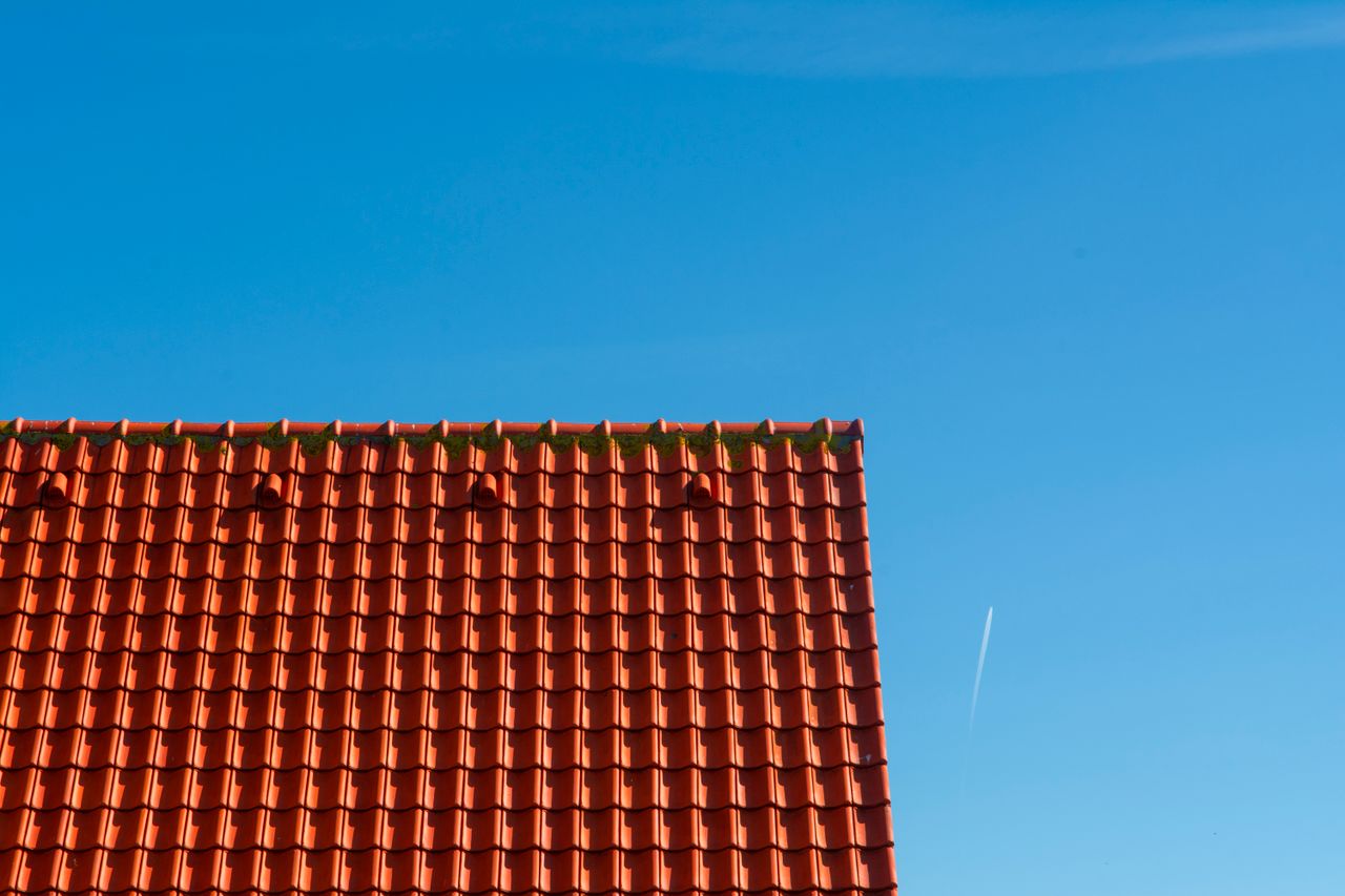 Completed red tiled rooftop contrasting against a clear blue sky