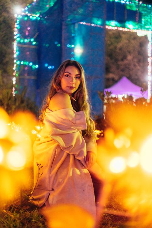 Free A captivating portrait of a woman surrounded by glowing lights in a vibrant outdoor setting. Stock Photo