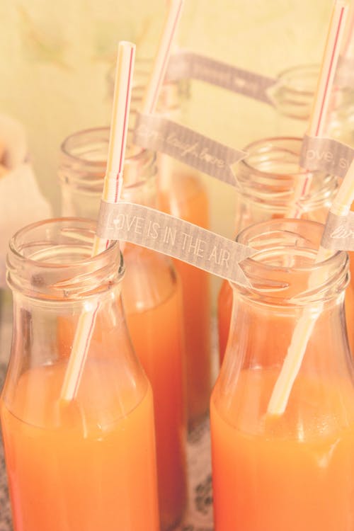 Pairs of Bottles of Juice with Love is in the Air Written on a Tape between the Straws 