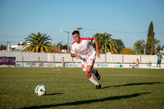 A young male soccer player in action during a match on a sunny day outdoors.