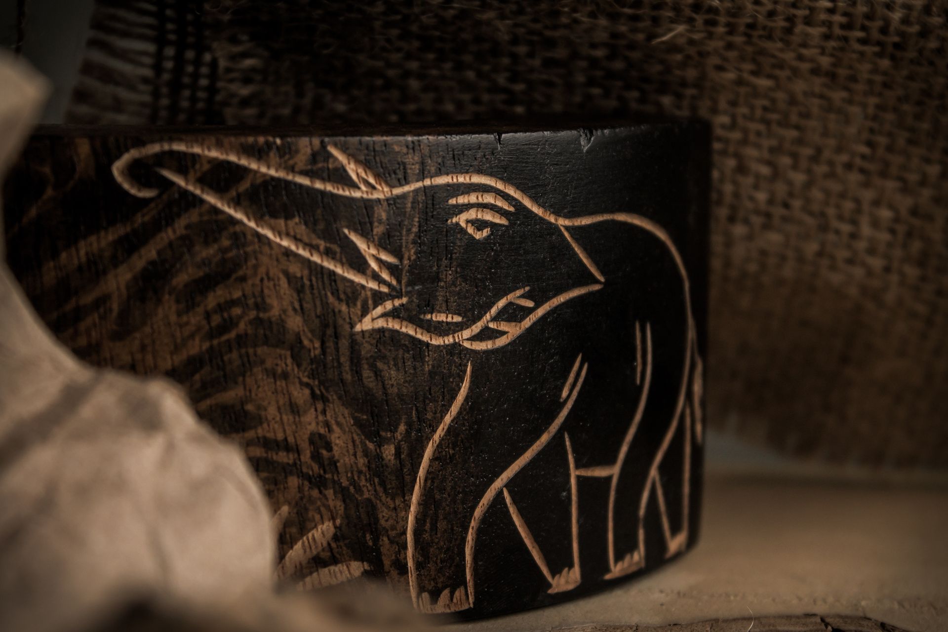 Artistic black wooden jar with handcrafted elephant carving, ideal for decor.