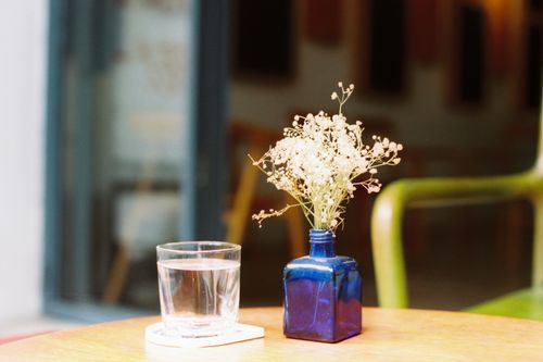Free A serene café table setting with a blue vase and glass of water, showcasing simple elegance. Stock Photo