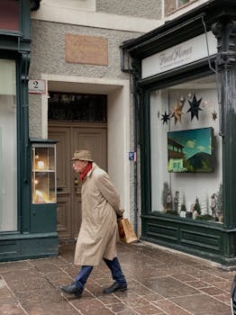 Elderly man in a coat and hat walks by shops in Salzburg, Austria.