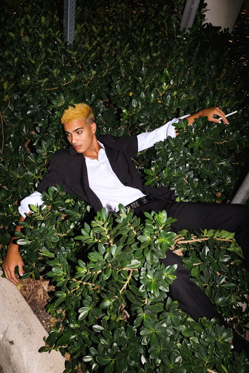 Man with a Cigarette in His Hand Lies in the Shrubs