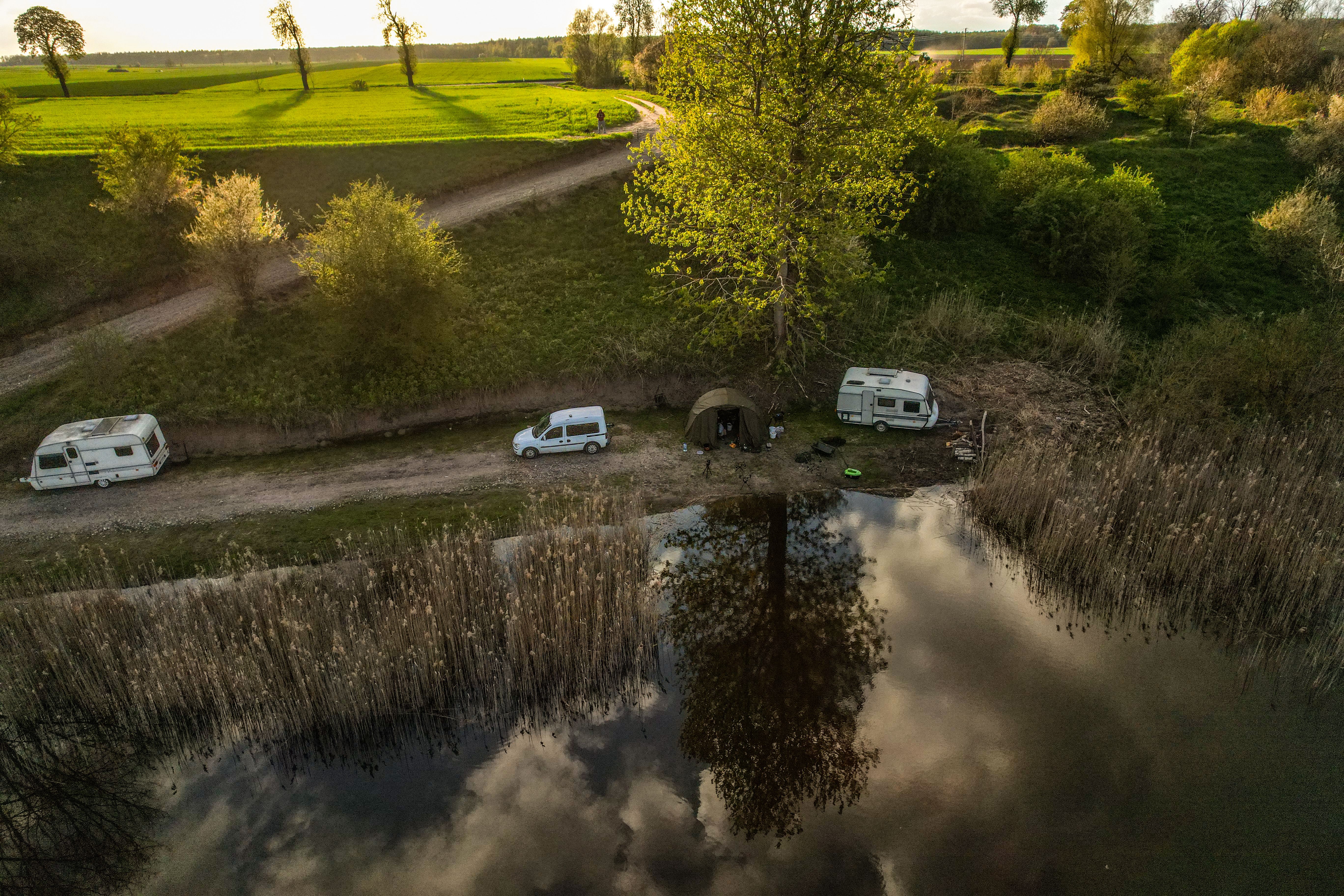 Luftaufnahme eines ruhigen Campingplatzes am See mit Wohnwagen und üppigem Grün