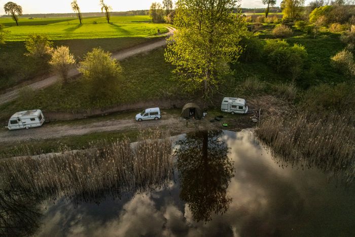 Aerial view of a lakeside campsite with caravans at first light — photo by Radoslaw Sikorski on Pexels